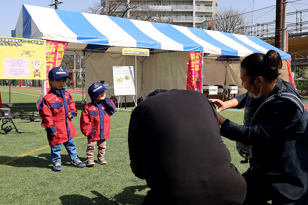 区の防災服を着て記念撮影をする子どもたち