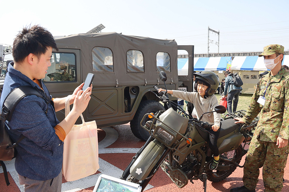 自衛隊のバイクにまたがって記念撮影をする男の子