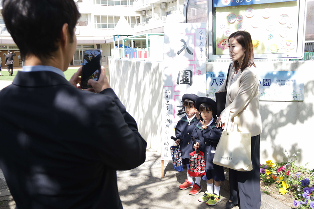 門の前に並ぶ子どもとお母さん