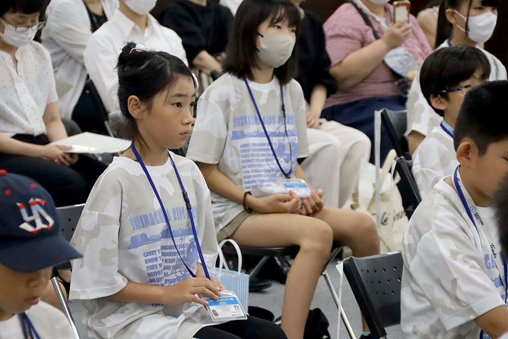 入隊証を触りながら区長の話を聞く女の子