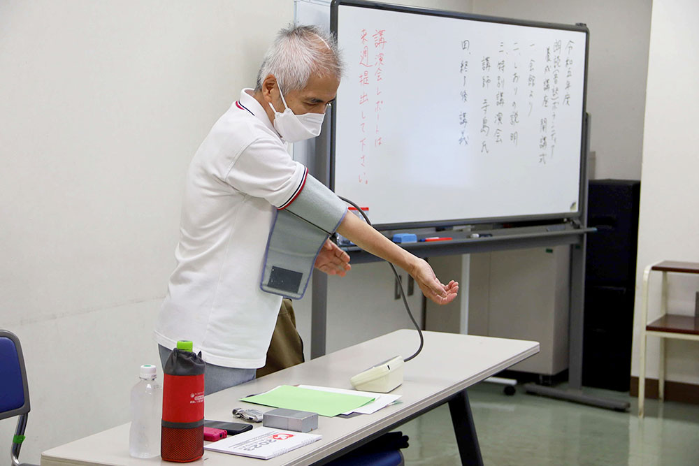 特別講演会講師の寺島さんが音声付き血圧計を使用する写真
