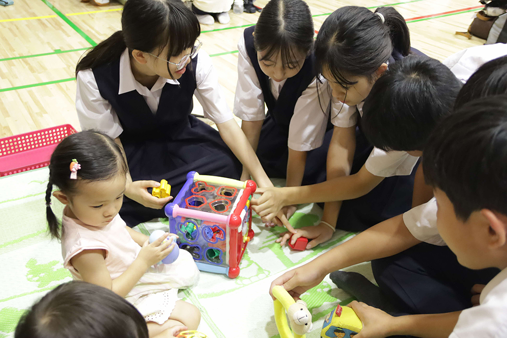 赤ちゃんとおもちゃで遊ぶ生徒たち