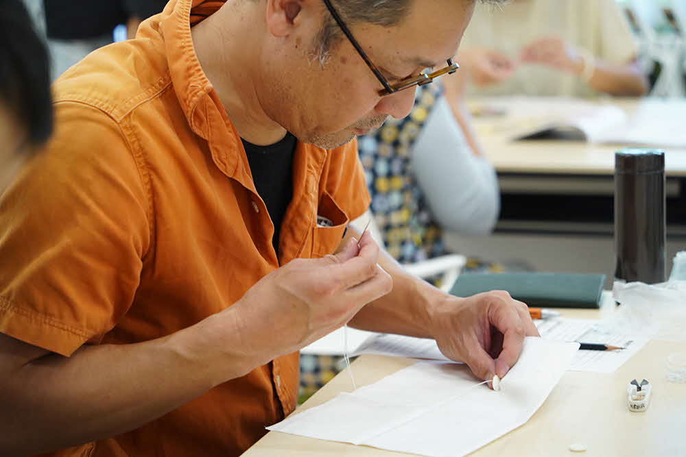 針を持って作業する男性の画像