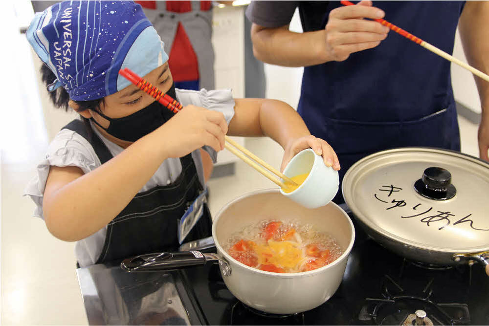 子どもがトマトと卵のスープを作っている写真