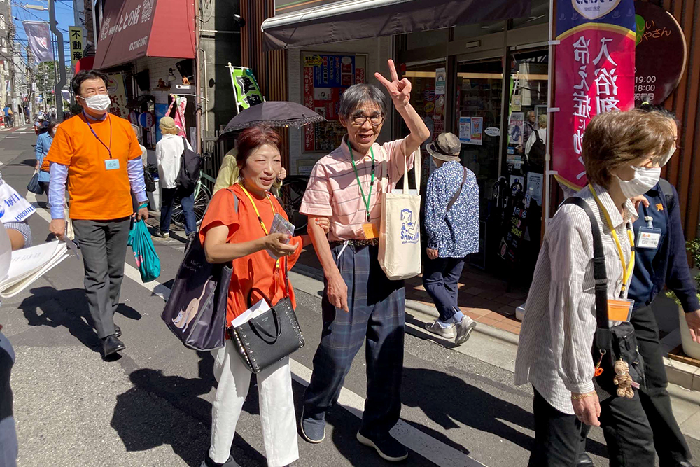 歩きながらカメラにピースをしている男性の画像