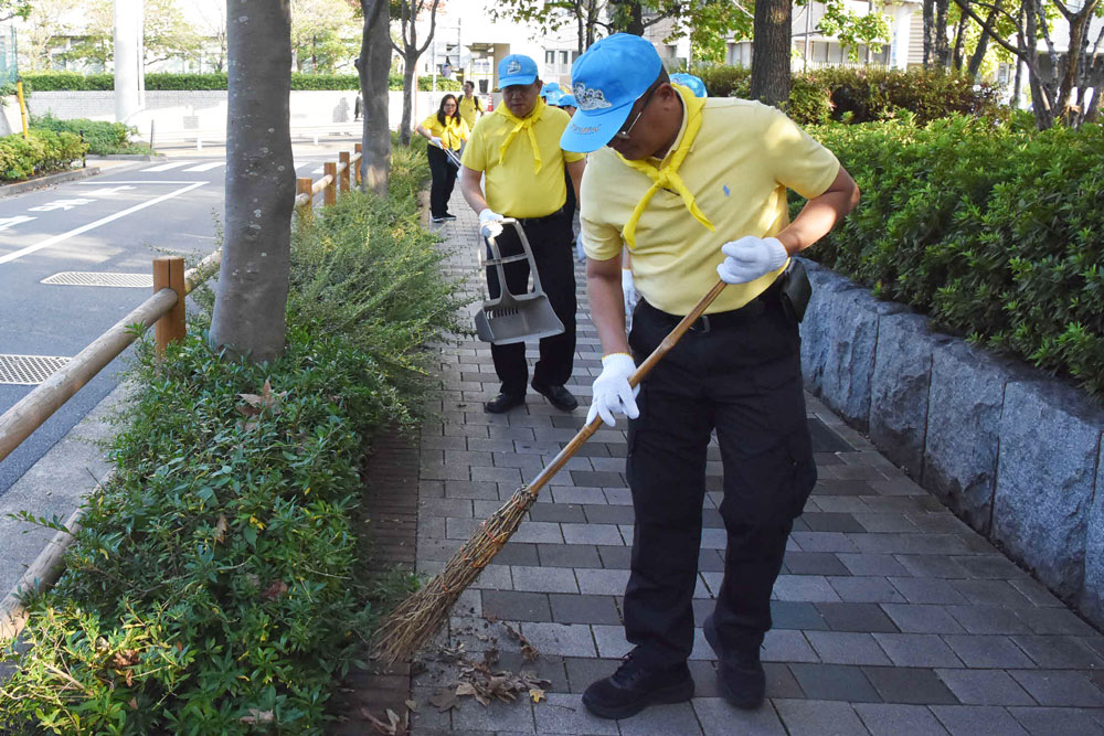 歩道をほうきで清掃している様子の写真