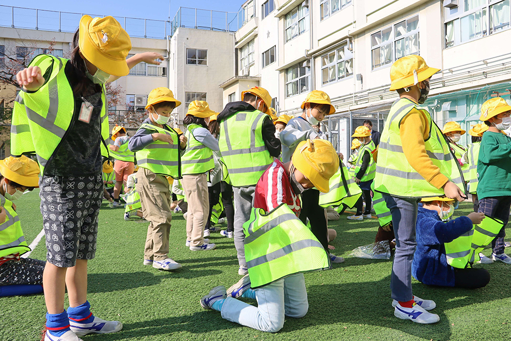 反射材ベストを着ようとしている子どもたちの画像