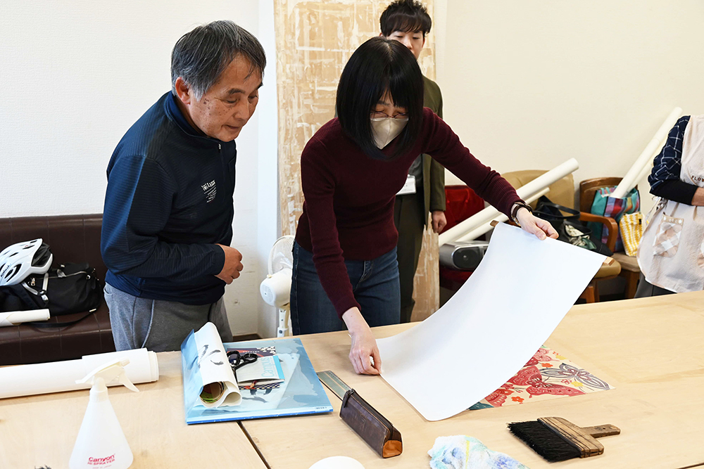 講師から指導されながら布に和紙を張る参加者の画像