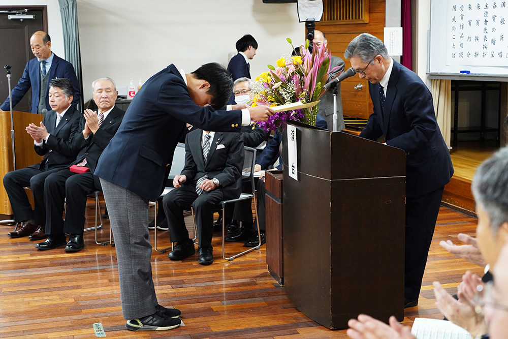 表彰状を受け取って頭を下げている男の子の画像