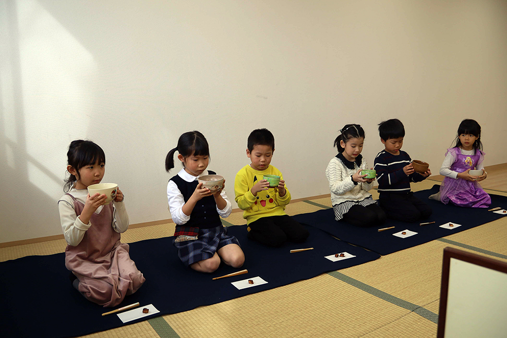 子どもたちが器を持ってお茶を飲んでいる写真