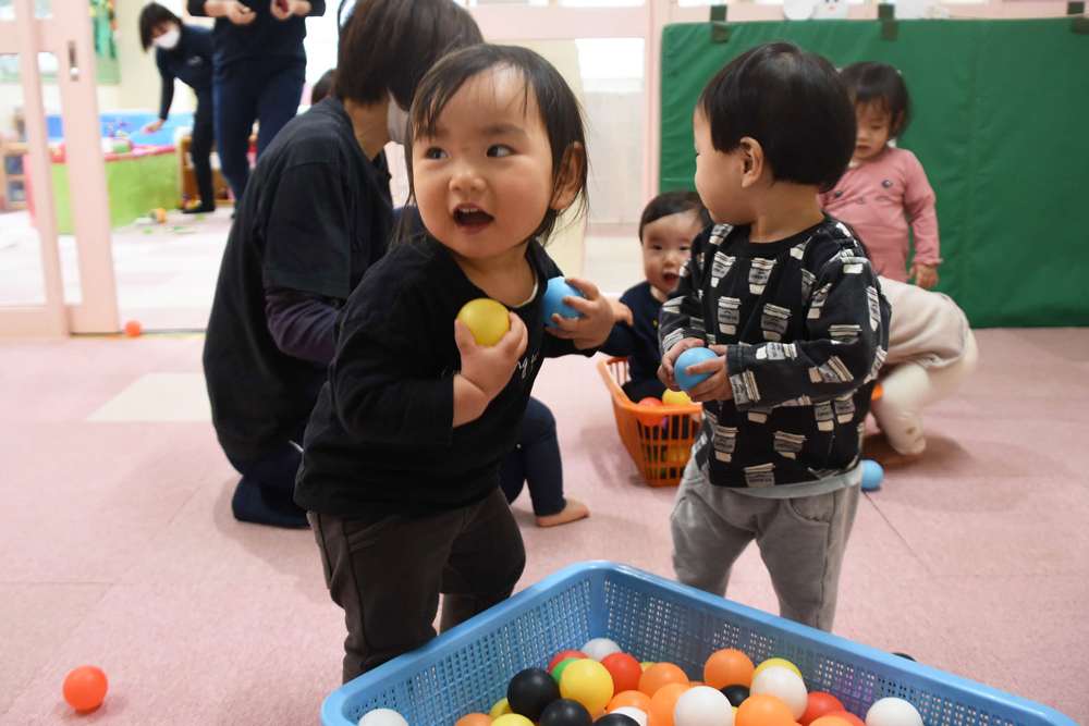 0歳児がボールを投げている様子の写真