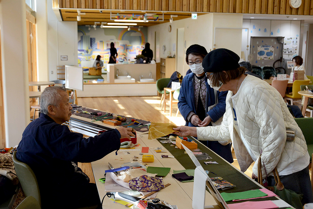 作品を手にした来場者と話す剣持さんの画像