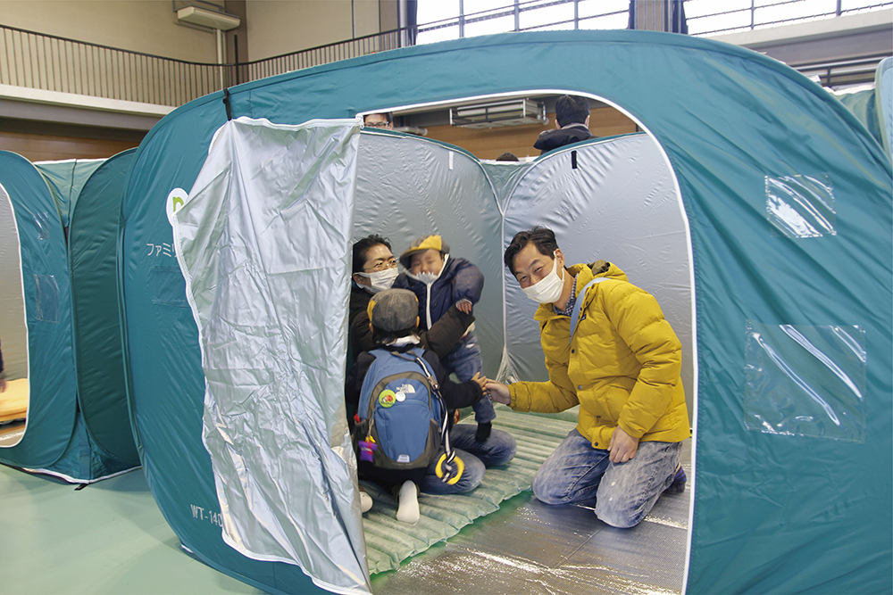 避難所開設訓練で建てたテントに入る親子の画像