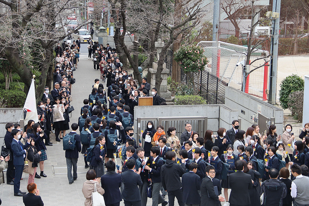 校門前で在校生や保護者に見送られている画像