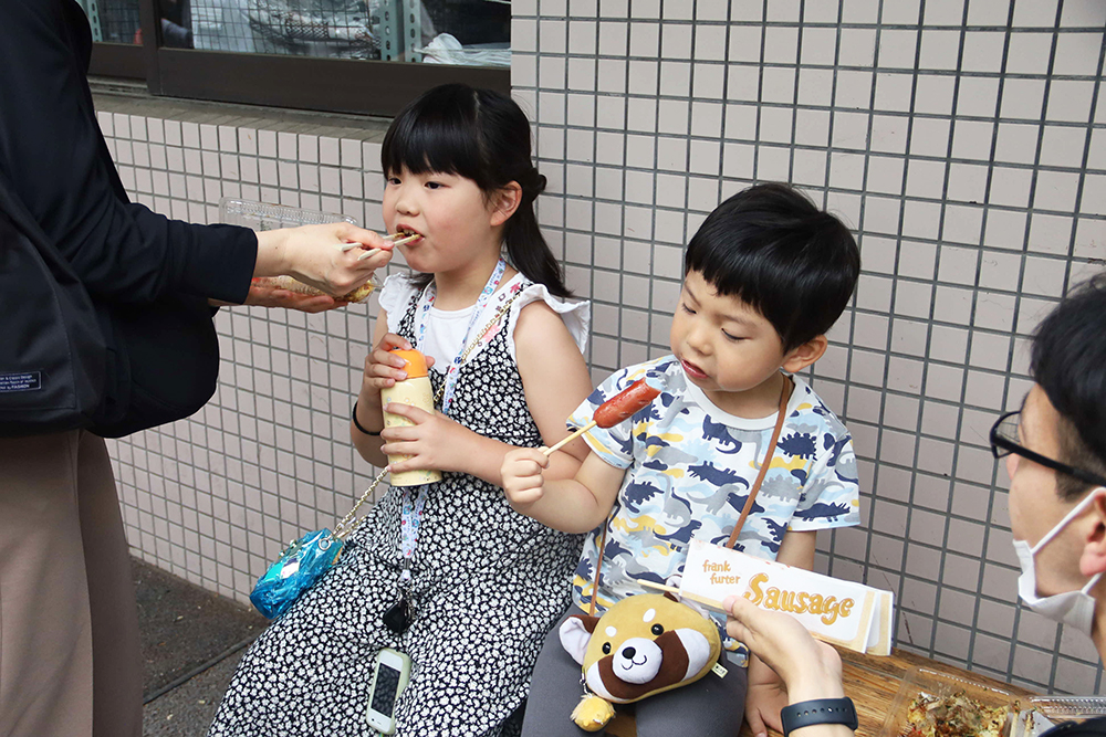 模擬店で買ったものを食べる親子の画像
