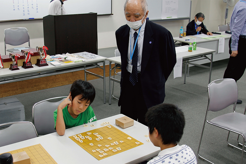 子どもが悩みながら将棋をしている写真