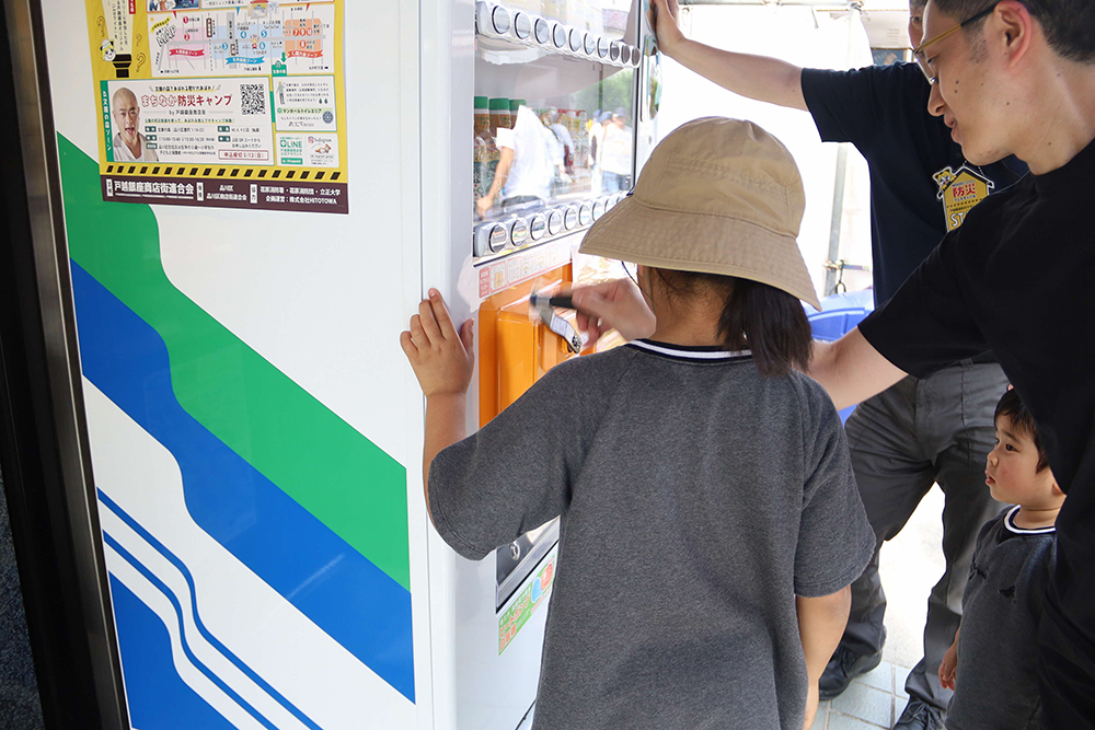 防災自動販売機を体験する親子の画像