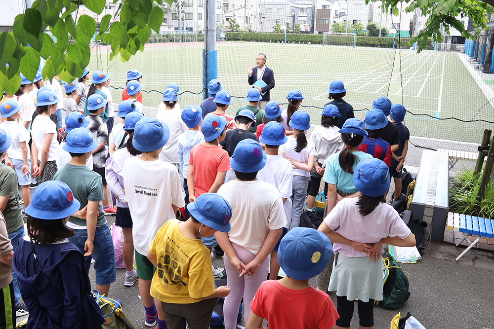 出発式で話をする校長と話を聞く児童たちの画像
