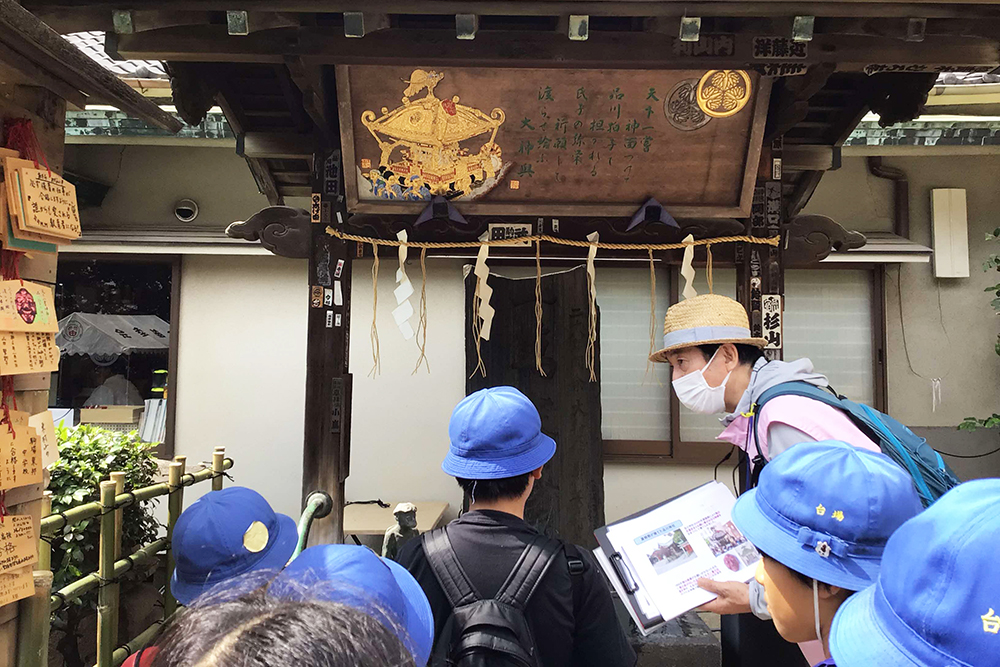 利田神社の説明をするガイドと話を聞く児童の画像