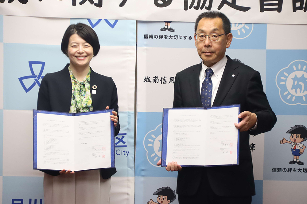 協定書を持って記念撮影する森澤区長と林理事の画像