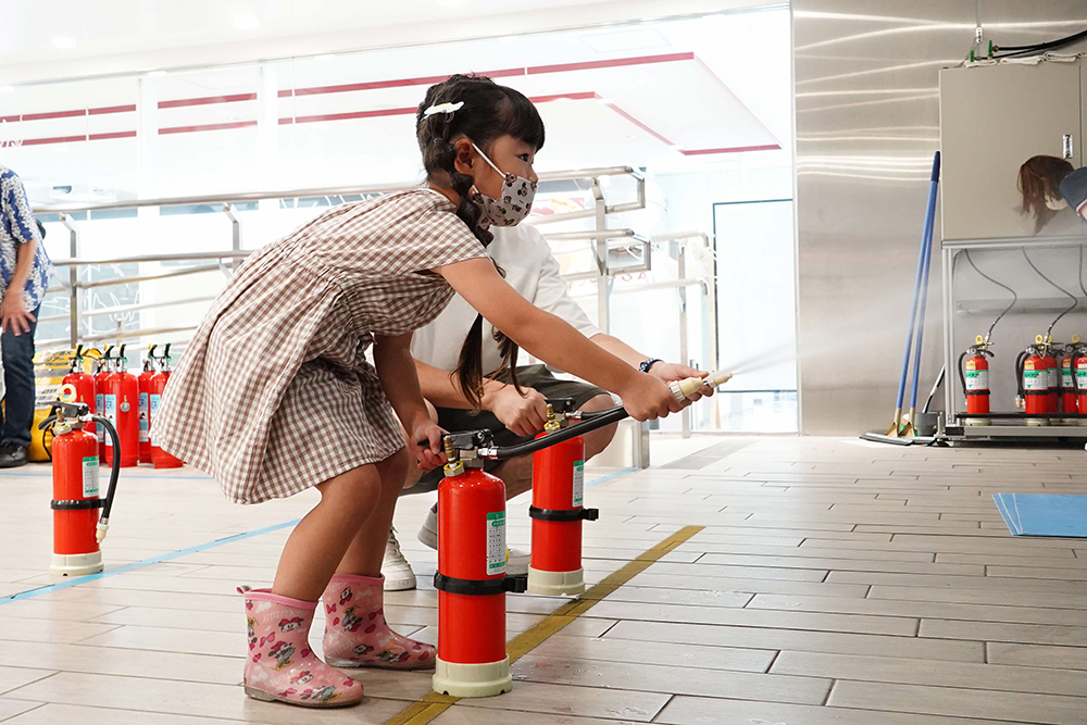 消火器で消火訓練をしている子どもの写真
