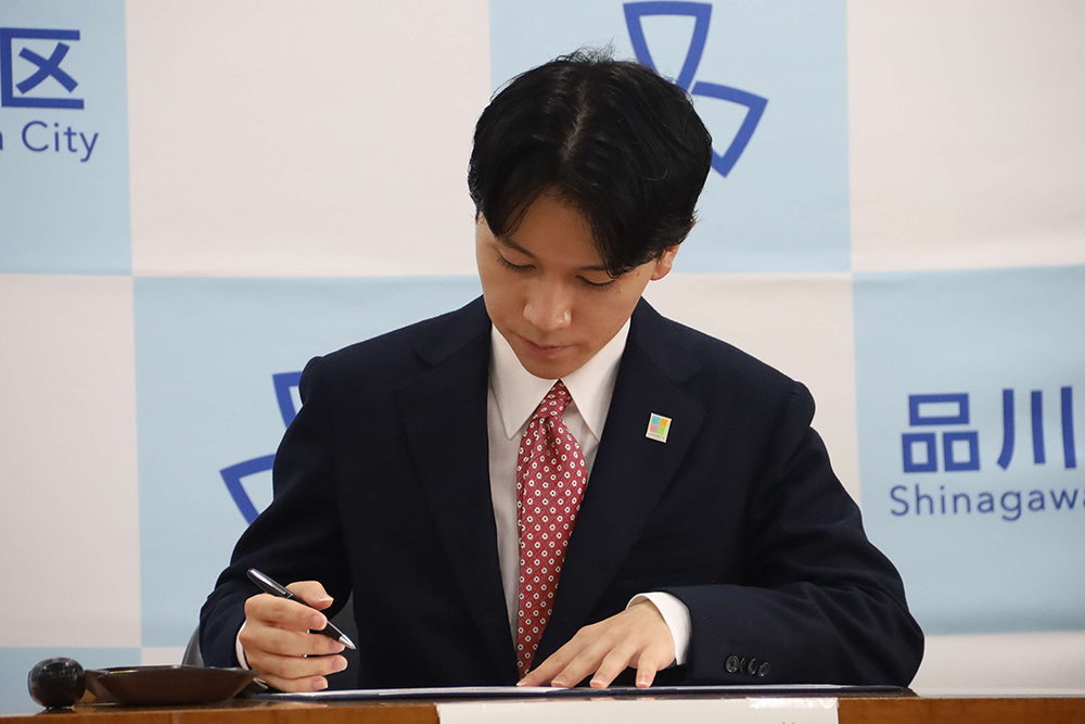 サインする大空理事長の画像