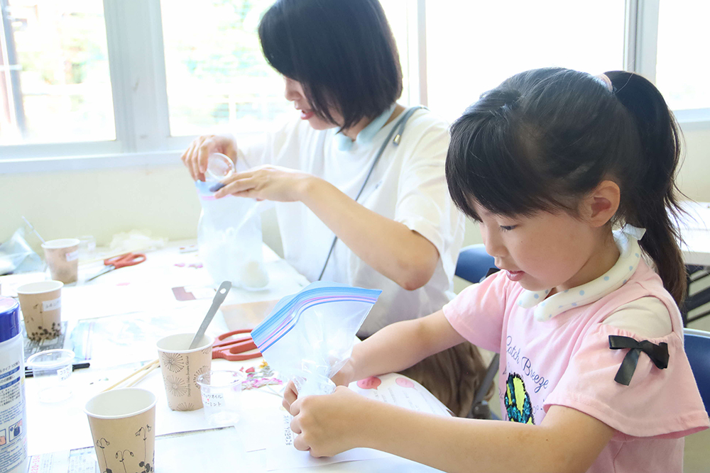 石鹸のもとをこねる親子の画像