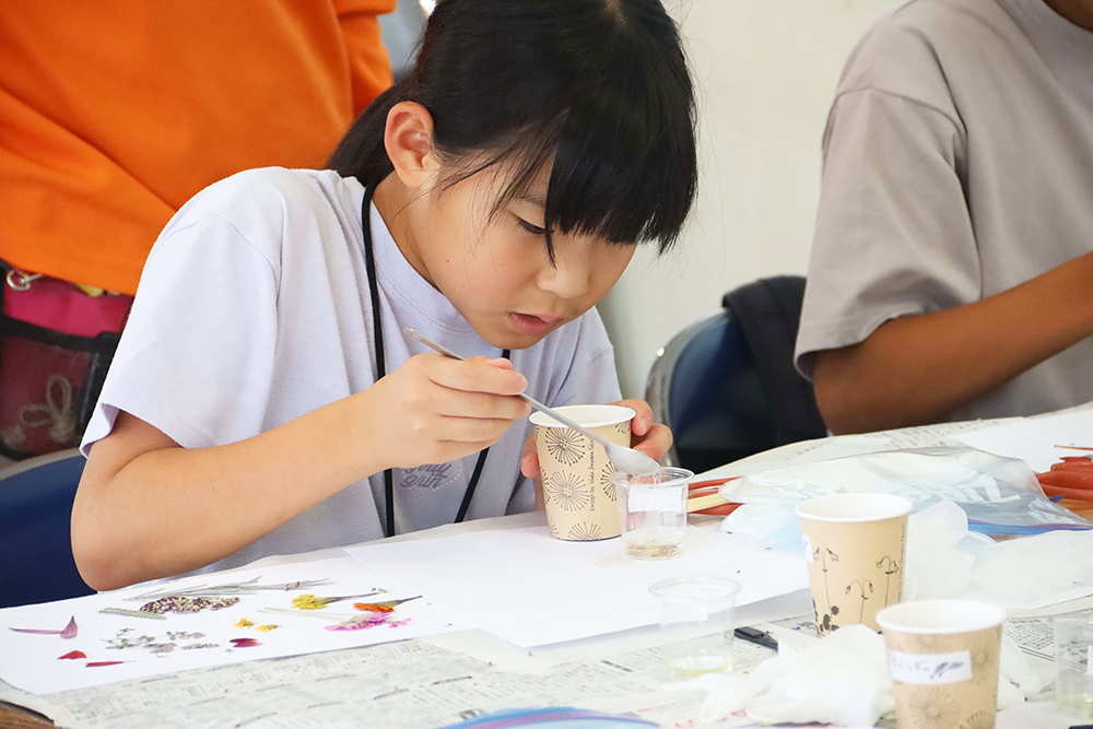 オイルを石鹸のもとに入れる子どもの画像