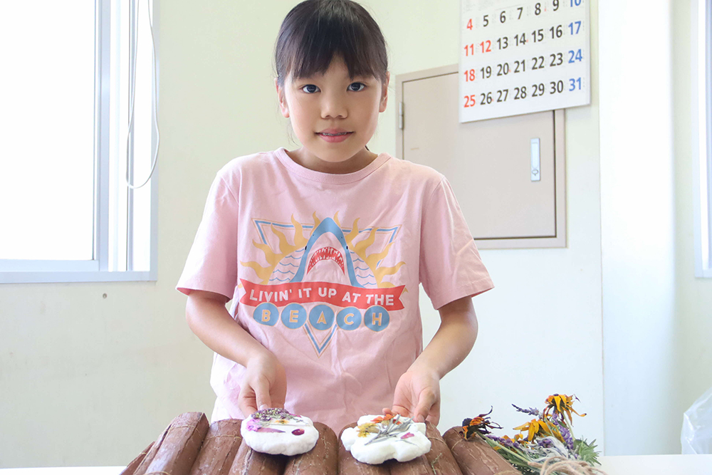 完成品を持って写真撮影する子どもの画像