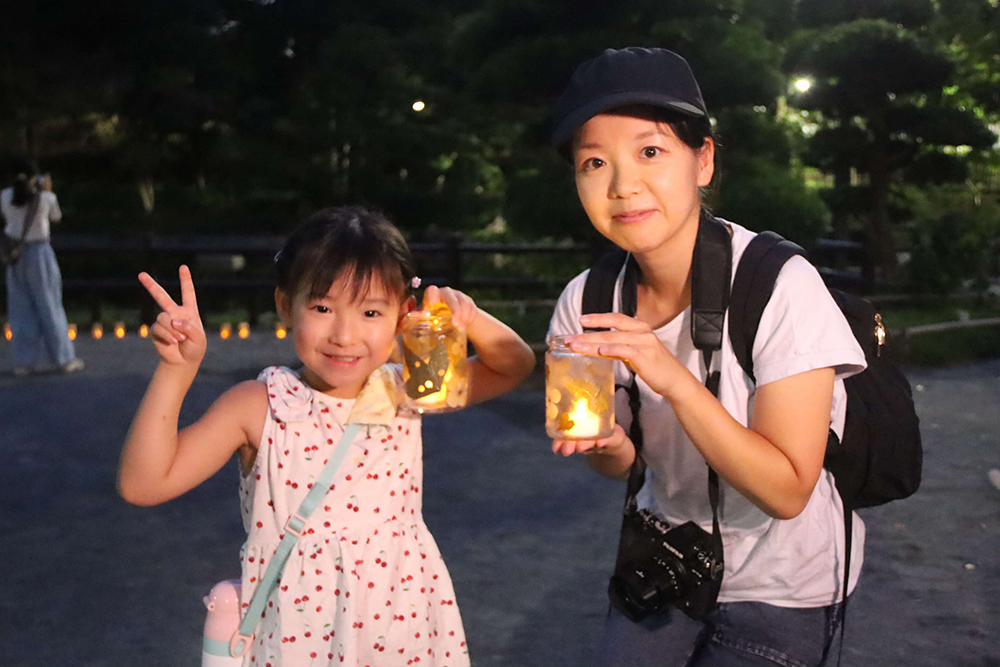 作ったキャンドルを持って写真撮影する親子の画像