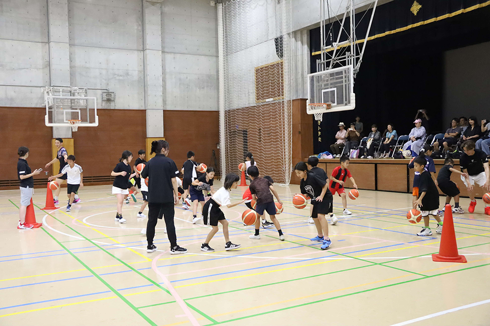 ドリブルの練習をする選手と子どもたちの画像