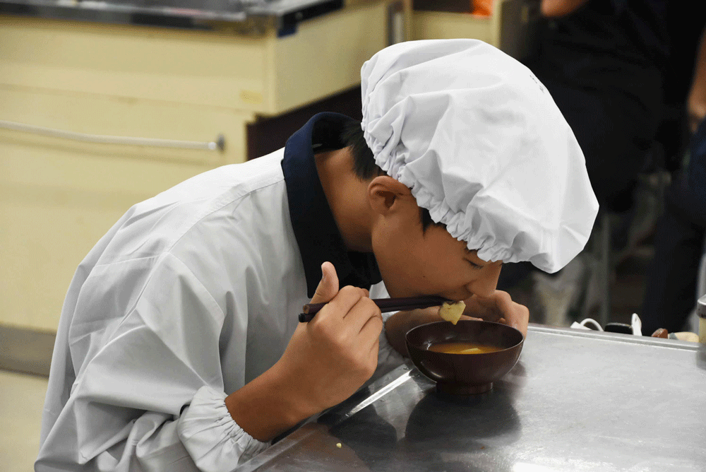 自分で作った味噌汁を食べる男子生徒