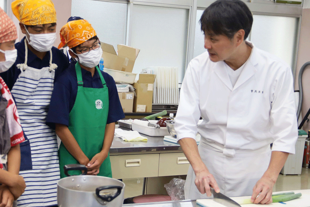 ねぎの切り方を見ている男子生徒たち