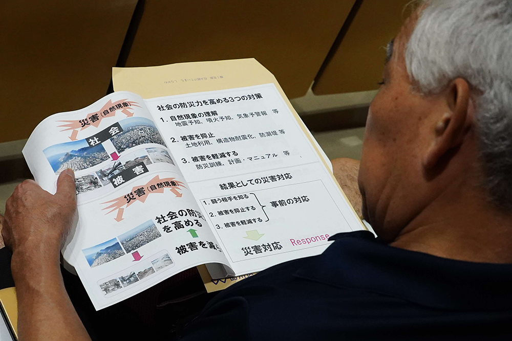 講演会資料を読む参加者の画像