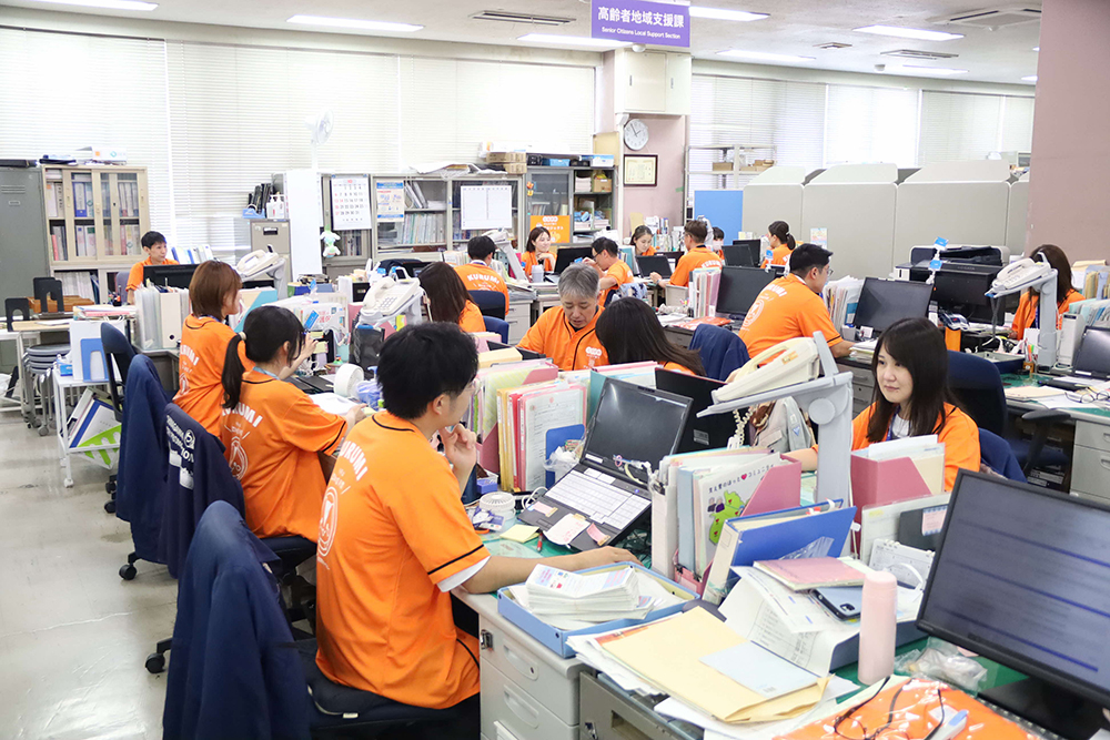 オレンジ色のTシャツを着た区職員たちの画像