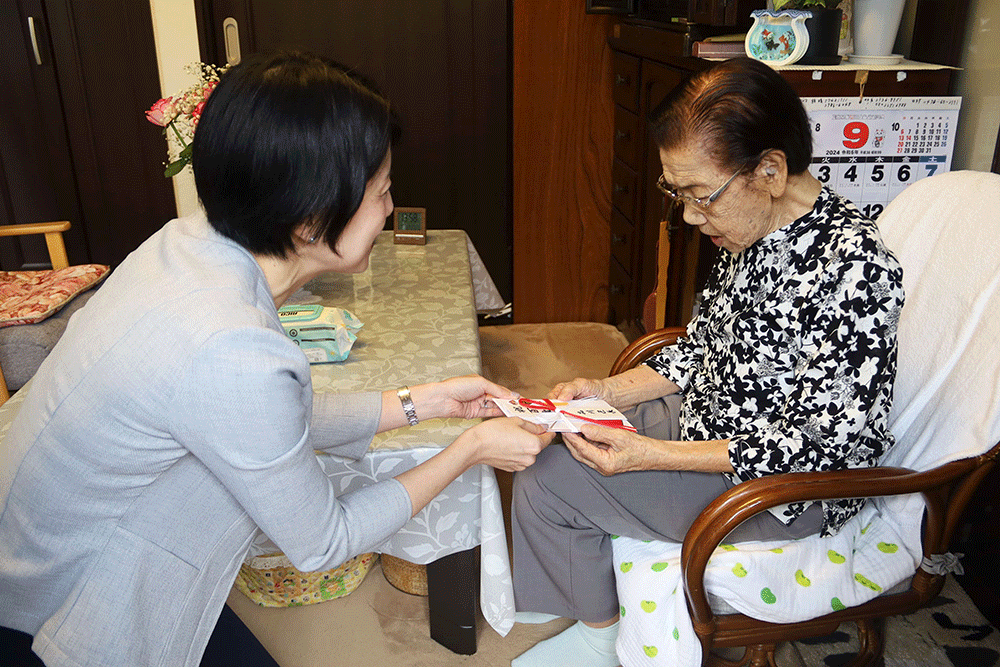 森澤区長がお祝い品を松尾さんへ渡している写真