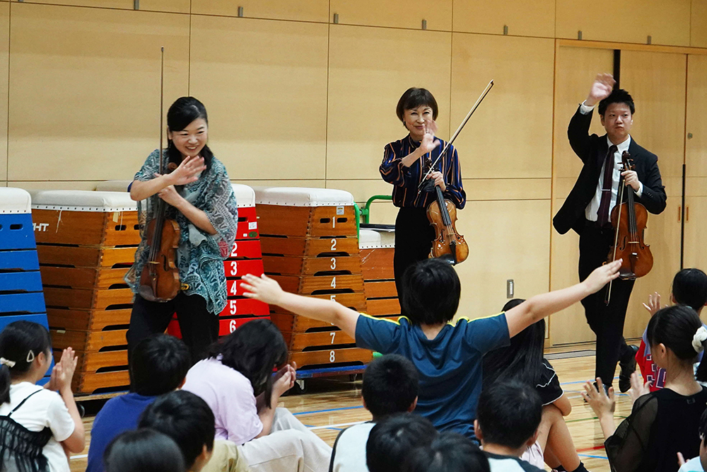 子どもたちに手を振る演奏者の画像