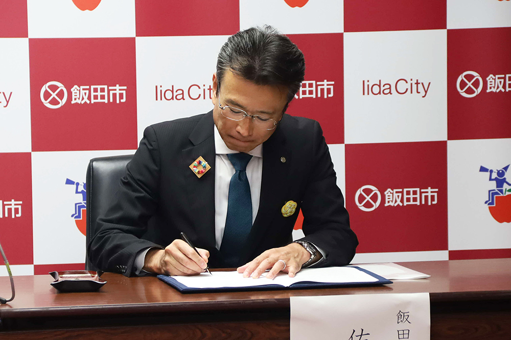 調印する佐藤市長の画像