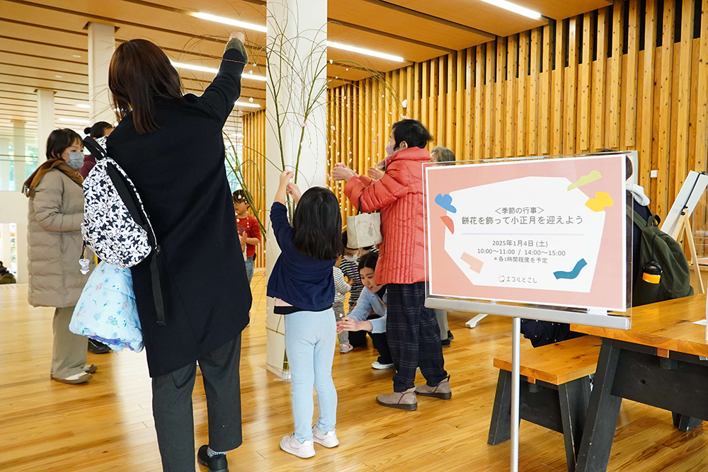 子どもや大人が柳の枝に餅を取り付けている写真