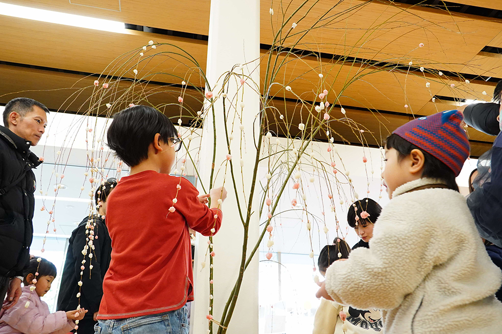 飾り付けられた餅花を眺めている写真