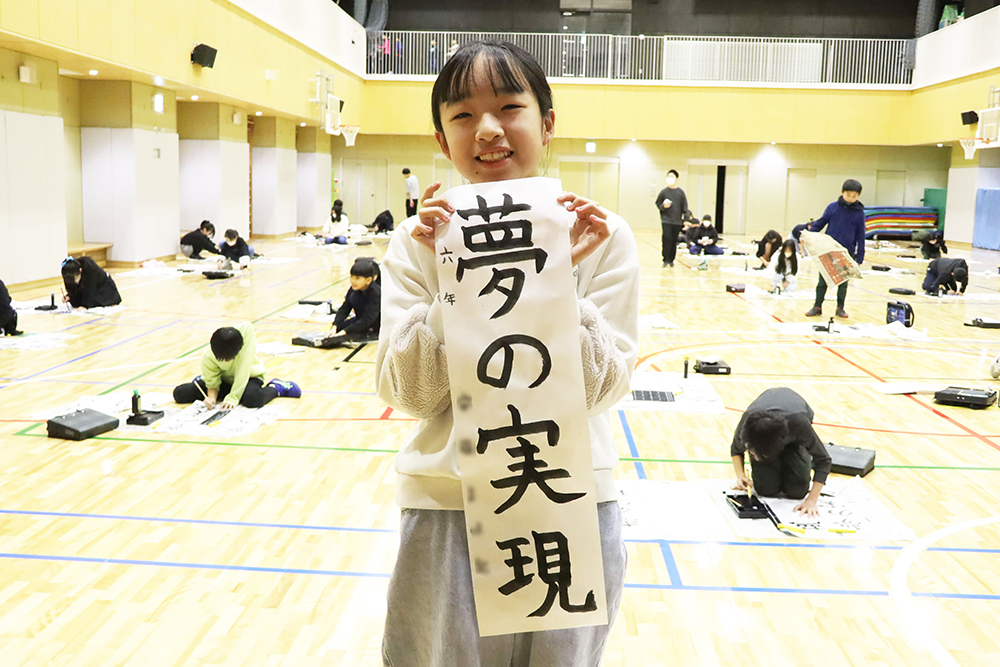 作品を持って写真撮影する児童の画像