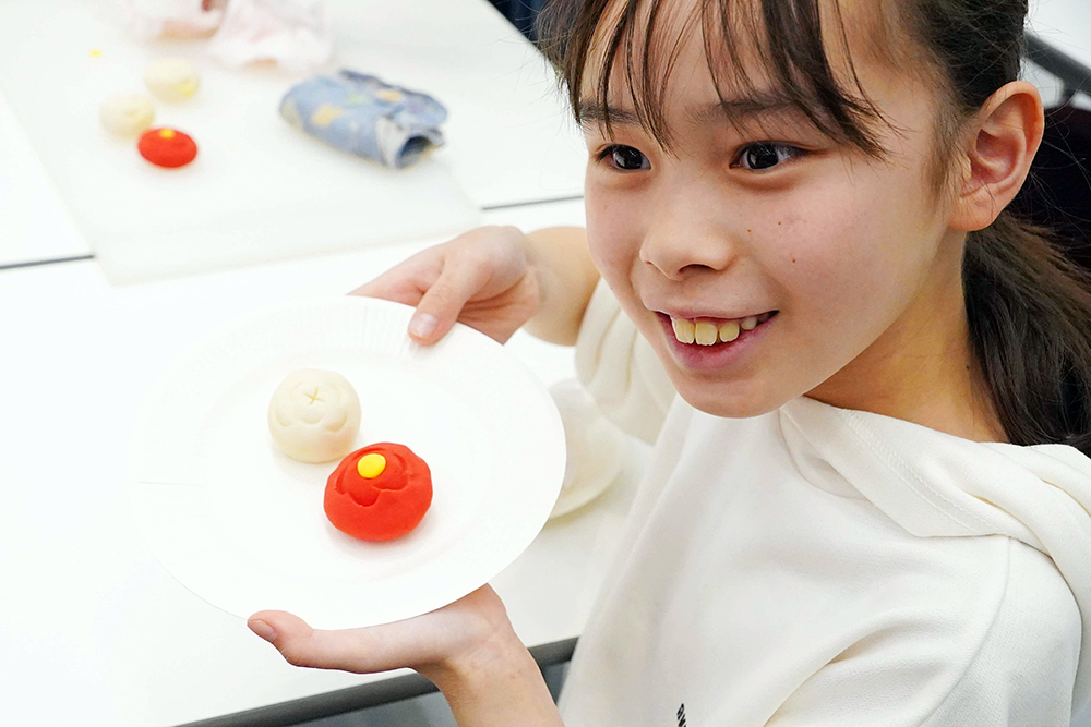 完成した和菓子を披露している子どもの写真