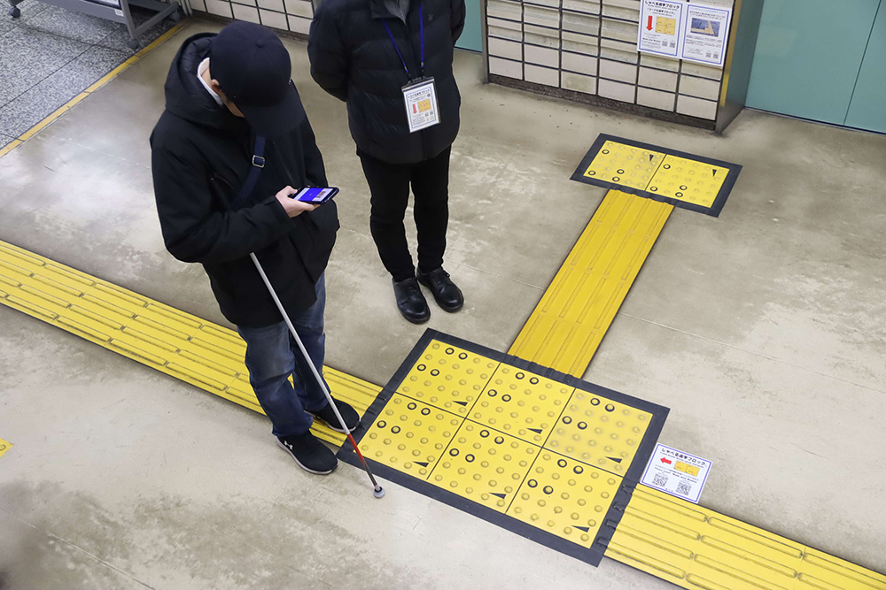庁舎内のコード化点字ブロックを読み取る参加者の画像