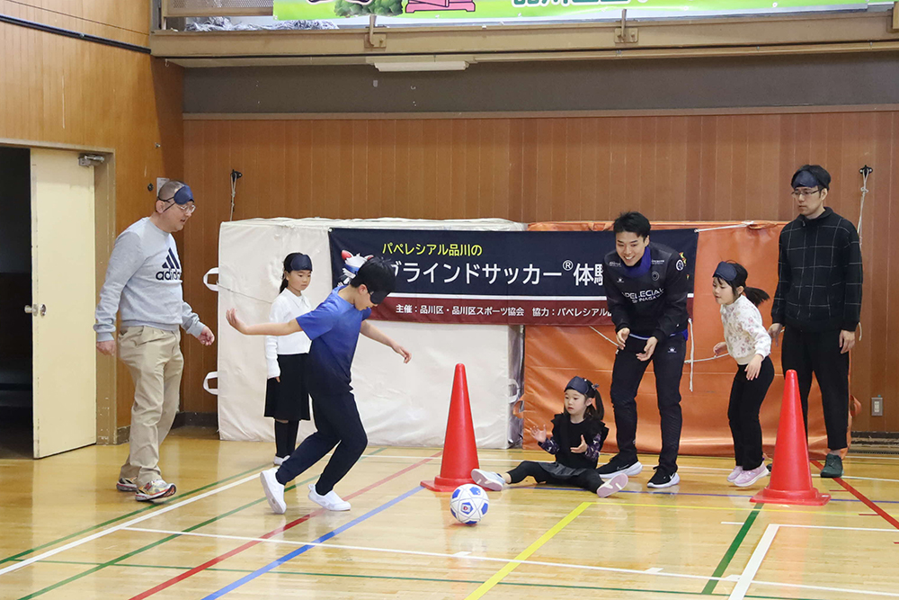 シュートする子どもと応援するチームメイトの画像