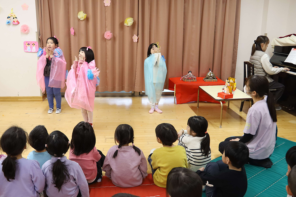歌を歌う園児とピアノを弾く保育士の画像