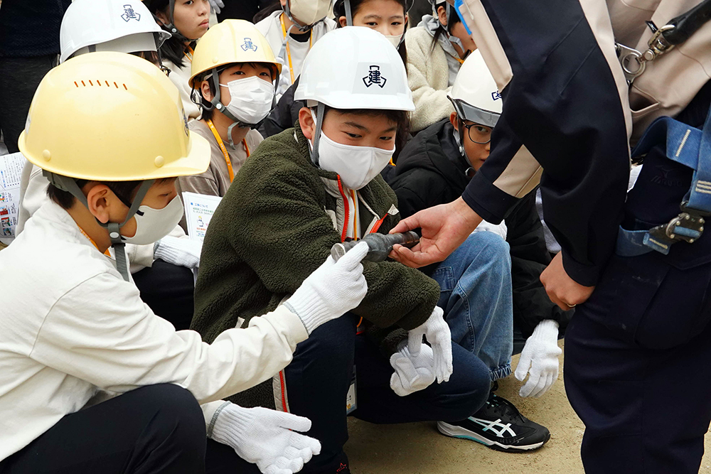 溶接された鉄筋に触れる子どもの写真