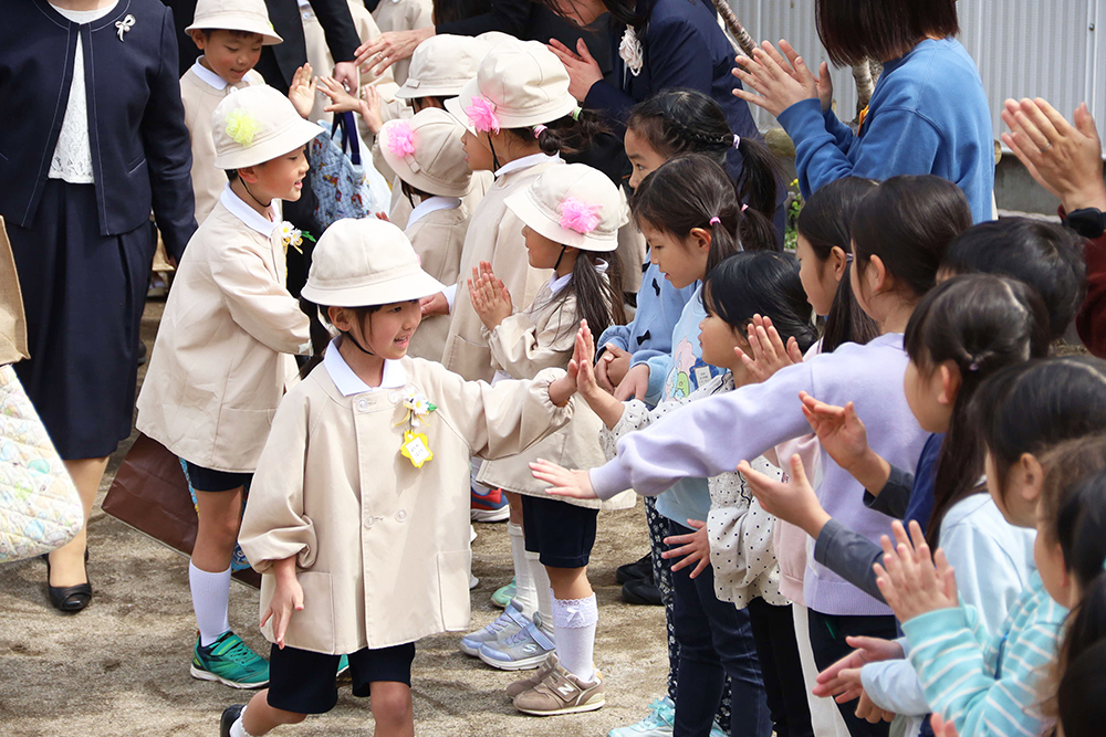 見送る在園児と見送られる卒園児の画像
