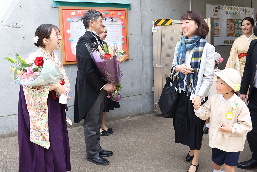 子どもを見送る園長と担任の画像