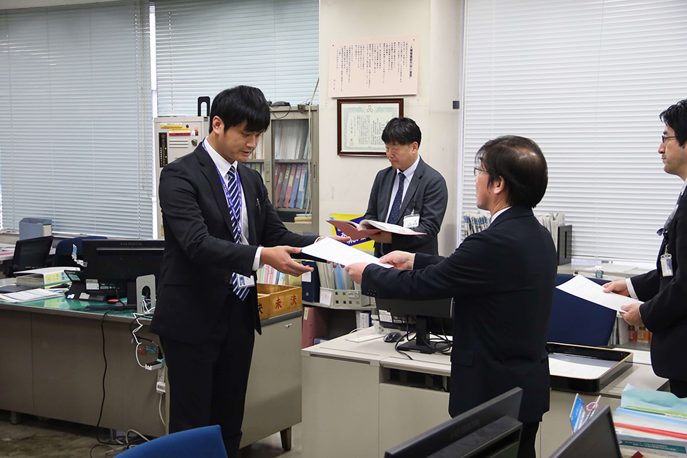 辞令を受ける新規採用職員と見守る職員たちの画像