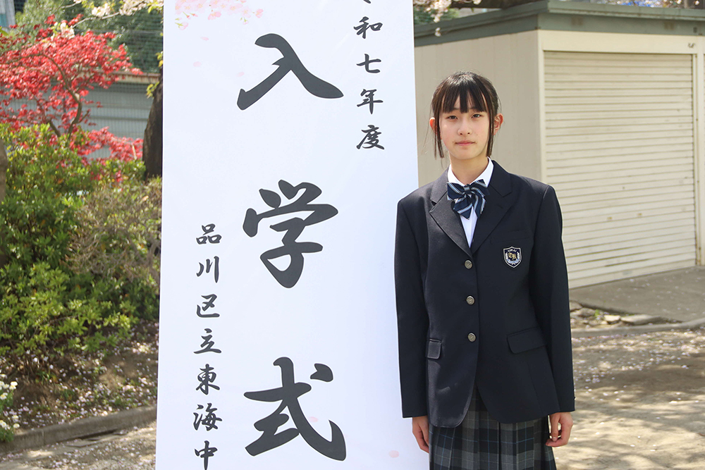 校門の前で記念撮影する7年生の画像